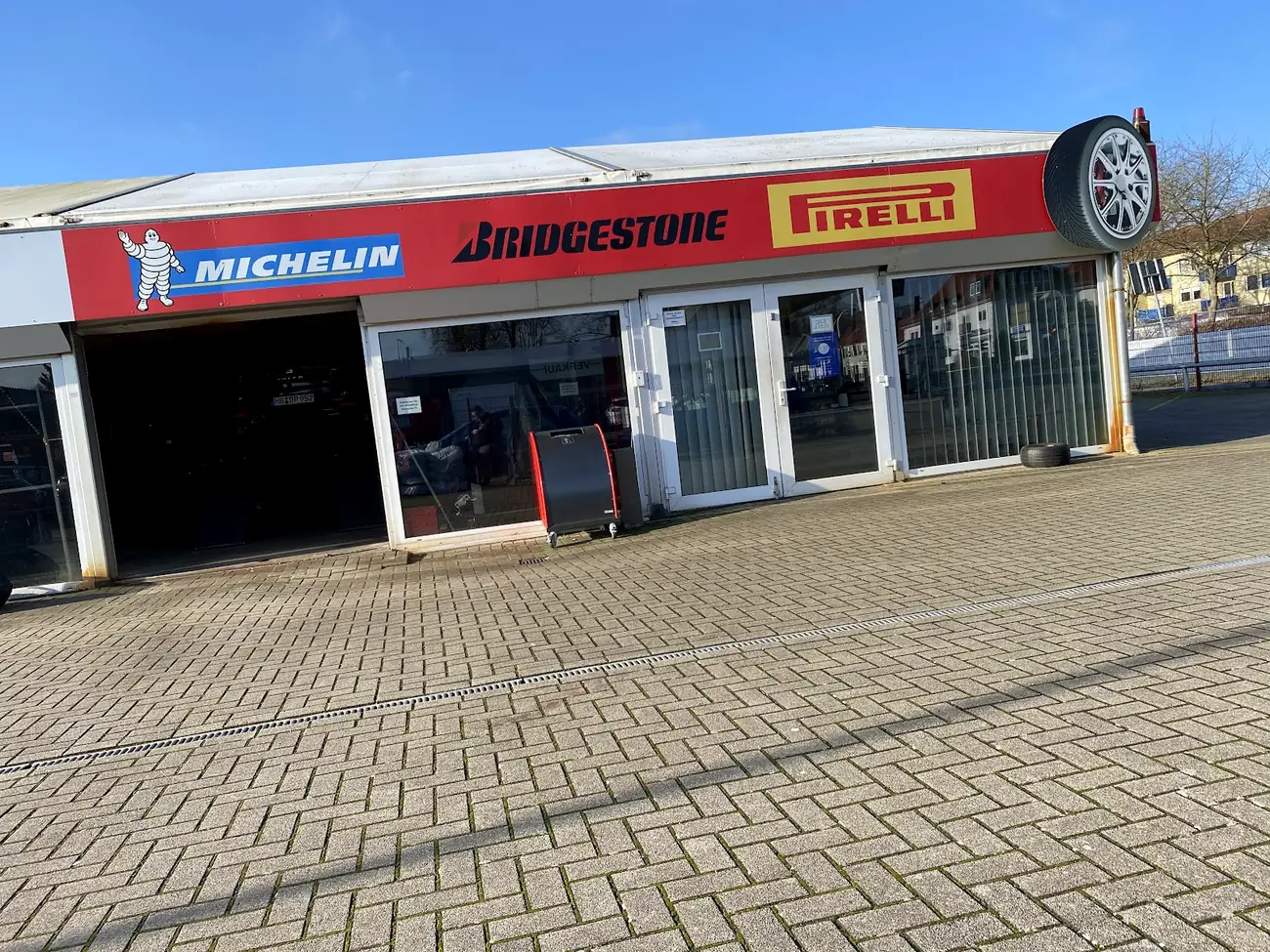 Frontansicht der Halle vom Reifen Treff mit Michelin-, Bridgestone- und Pirelli-Schildern