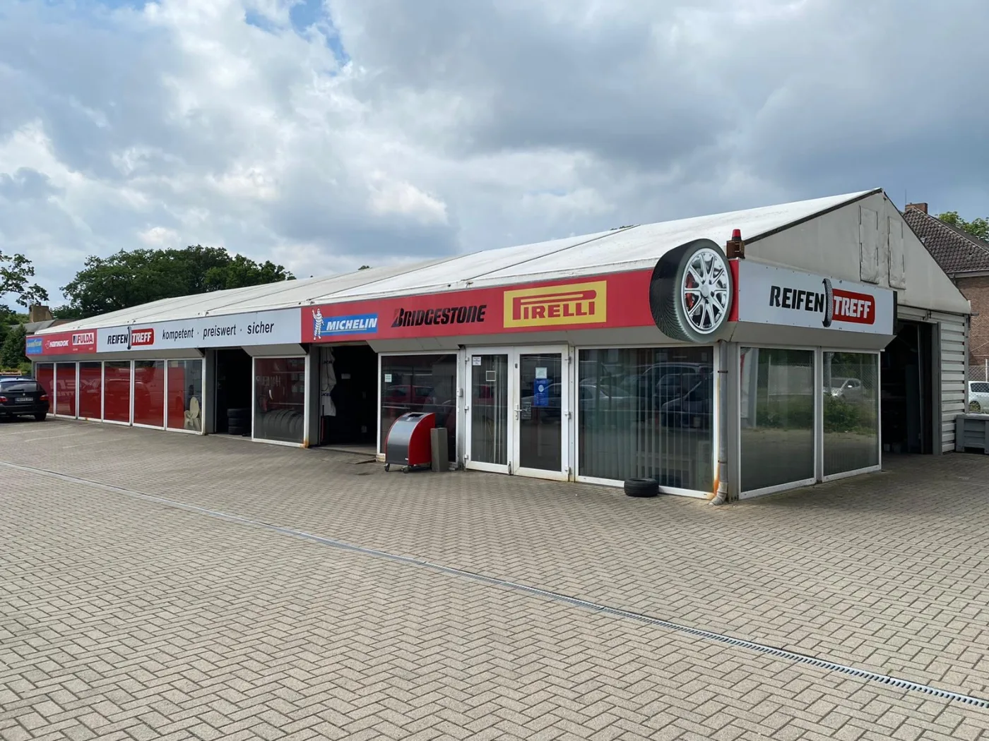 Frontansicht der Halle vom Reifen Treff mit Michelin-, Bridgestone- und Pirelli-Schildern